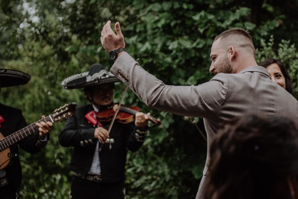 Zwei Mariachi-Musiker spielen Geige und Gitarre vor einem Hochzeitsgast